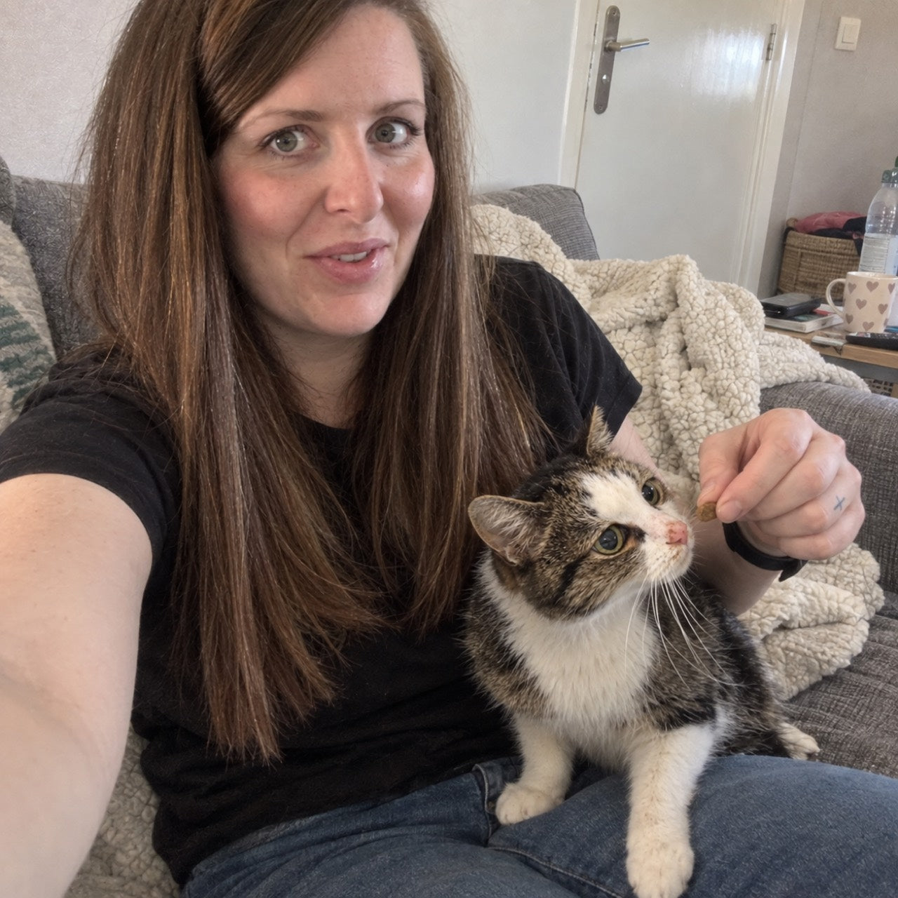 Selfie reconstitué par IA à partir des photos fournies : Coline propose une friandise à son chat sur ses genoux.