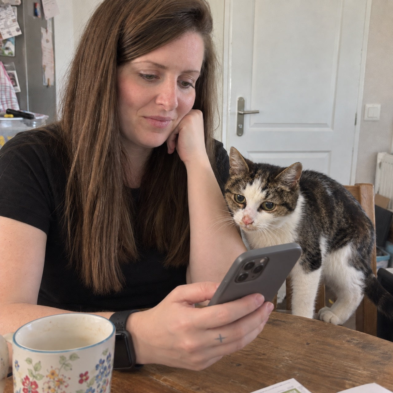 Scène reconstituée par IA : Coline consulte une page de composition sur son téléphone, son chat près d’elle.